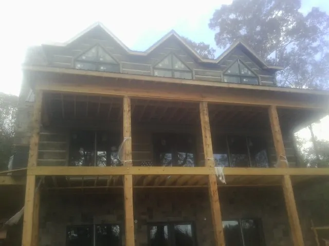 Dormers and porch framing on a large log home under construction — Roof Coating work by our crew in Mount Morris